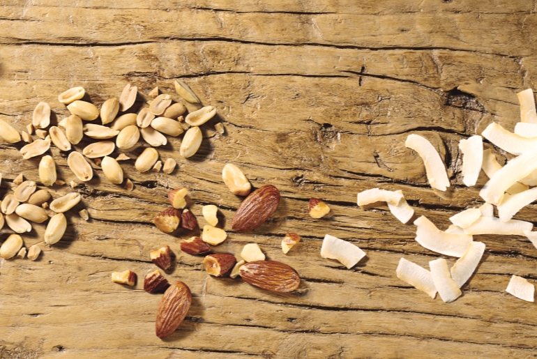 Pine nuts and sliced almonds scattered on a rustic wooden table
