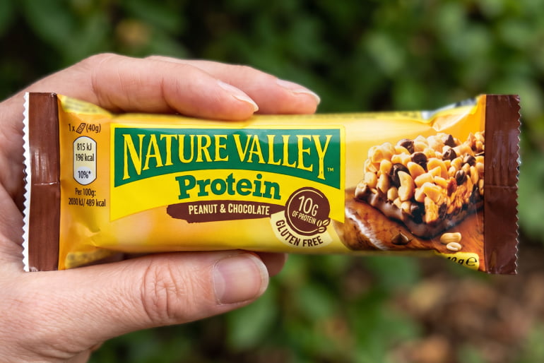 Hand holding a Nature Valley Protein bar, peanut & chocolate, gluten free, 10g protein