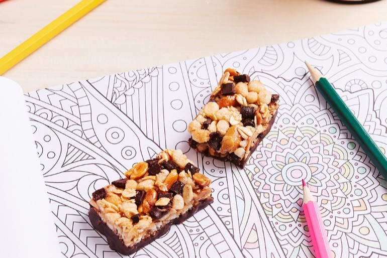 Two chocolate-and-nut dessert squares on a patterned paper with a green and pink marker pen nearby