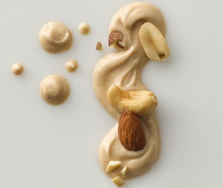 A sculpted dollop of beige food shaped like a person, with small round pieces and a brown oval piece.