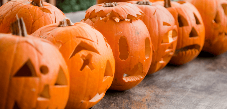 A row of orange coloured Pumpkins crafted to look like human faces.